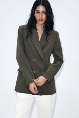 Blazer blanco de manga larga con cuello solapa y hombreras. Diseño cruzado con cierre frontal de cuatro botones y bolsillos delanteros con solapa.