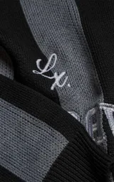 Sweater de punto con diseño a rayas verticales en negro y gris, cuello redondo y mangas largas. Presenta un estampado gráfico frontal con estilo deportivo retro que incluye el texto 'Ravers' y el número '90'. Cuenta con terminaciones en punto rib en cuello, puños y ruedo.