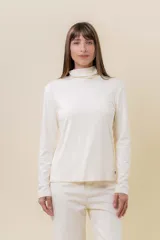 Polera de manga larga en color crudo, confeccionada en tejido suave y liviano con leve elasticidad. Presenta un cuello alto tipo tortuga y un calce regular, ideal para usar como prenda base o sola.