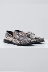 Mocasín negro de cuero con textura tipo cocodrilo, detalle de estribo metálico plateado en el empeine y costuras reforzadas en la puntera.