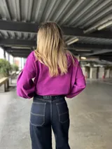 Canguro con capucha y cordones ajustables, confeccionado en tejido de punto. Presenta mangas largas abullonadas con puños elásticos y un parche de cuero sintético con logo en el pecho.