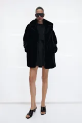 Abrigo de Zara con efecto pelo, cuello de solapa con muescas, manga larga y bolsillos delanteros. Cuenta con forro interior a tono y cierre frontal mediante ganchos metálicos.