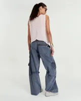 Pantalón cargo de tiro medio confeccionado en gabardina de algodón y lino con efecto gastado. Presenta una silueta de pierna recta y ancha, con bolsillos laterales inclinados y bolsillos cargo con tapa en las rodillas. Incluye tiras ajustables con hebillas metálicas en los laterales para modificar la silueta, cierre metálico y bolsillos traseros.