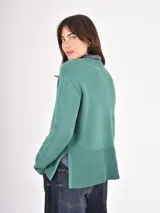Buzo de tejido de punto color negro, con cuello redondo, mangas largas y puños anchos acanalados. Presenta un diseño con ruedo asimétrico y aberturas laterales.