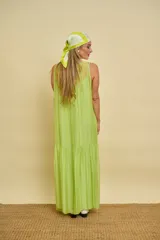Vestido largo sin mangas de color verde lima, confeccionado en tela fluida y ligera, con escote redondo y corte amplio.