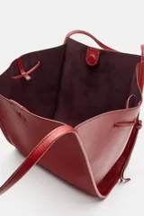 Bolso tipo shopper color rojo de hombro, con detalle de lazos en los laterales y doble asa.