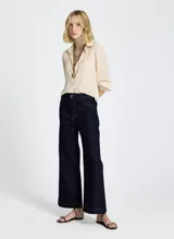 Pantalón de jean de tiro alto, color azul oscuro, con corte flare y costuras en color ocre.