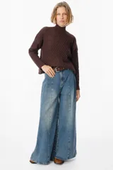 Jean de corte wide leg con pinzas frontales y costuras verticales decorativas. Presenta un diseño de tiro alto con cierre de botón y cremallera, confeccionado en denim de lavado medio.