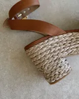 Sandalias de plataforma con capellada de cuero color marrón, tobillera con hebilla dorada y base de rafia.
