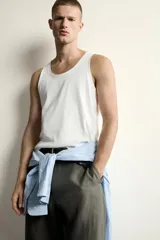 Camiseta sin mangas tipo tank top de corte slim fit, confeccionada en tejido de algodón con elasticidad, cuello redondo amplio y vivos en tejido combinado a tono.