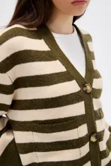 Saco de punto con diseño de rayas horizontales en tonos beige y marrón, cuello en V, cierre frontal con botones y bolsillos laterales. Presenta un corte holgado y mangas largas con puños acanalados.