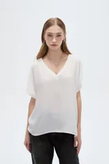 Blusa blanca de poliéster de corte holgado, con escote en V y mangas cortas.