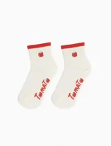 Medias cortas de color blanco con borde superior en color rojo, decoradas con un pequeño estampado de tomate y la palabra 'Tomato' en el lateral.
