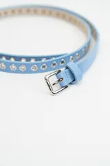 Cinturón fino de cuero sintético color celeste, con perforaciones metálicas a lo largo de toda la tira y hebilla metálica plateada.