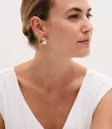 Kit de tres pares de aros tipo argolla en baño dorado. Incluye un par con botón de nácar, un par con textura metálica y un par con detalle de nácar y strass.