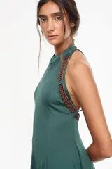Vestido largo azul marino, de corte fluido, con escote halter, detalles trenzados en los hombros, bolsillos laterales y tajo profundo en la pierna.