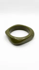 Pulsera rígida de acrílico en tono verde militar, con diseño asimétrico y acabado brillante.