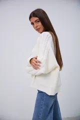 Sweater blanco de punto trenzado, con cuello redondo y mangas largas.