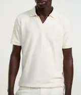 Remera polo de hombre en color marrón, confeccionada en tejido texturizado con mezcla de algodón y poliéster, de manga corta y cuello abierto sin botones.
