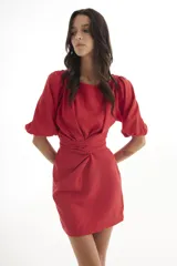 Vestido corto de lino color rojo, con mangas globo y escote redondo. Presenta un corte entallado en la cintura con un lazo ajustable que permite entallar la prenda.