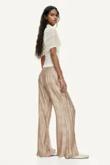 Pantalón wide leg de tejido plisado con ligero brillo, color beige, con cintura elástica y bolsillos laterales.