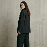 Blazer negro de corte sastrero con diseño de rayas diplomáticas verticales, cierre frontal de un botón y bolsillos laterales con solapa.