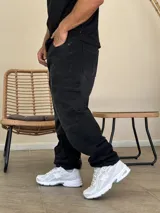 Pantalón tipo cargo de denim color negro con efecto lavado. Presenta corte holgado, bolsillos laterales con solapa y costuras reforzadas en las rodillas.