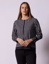 Blusa de gasa estampada a rayas verticales blancas y negras, marca Sioni. Espalda con abertura y botón. Manga larga con puño y botón.