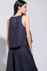 Top azul marino sin mangas, de corte holgado, escote redondo y detalle de tachas plateadas en los laterales.