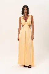 Vestido largo de satén color amarillo pastel, con escote en V profundo, aberturas laterales en la cintura y falda amplia con tajo lateral.