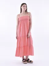 Vestido largo coral con escote recto fruncido tipo nido de abeja, tirantes finos y diseño escalonado en la falda con volados sutiles.