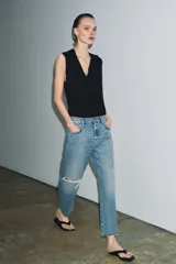Jeans de tiro medio con corte recto y largo al tobillo. Presentan diseño de cinco bolsillos, cierre frontal con cremallera y botón, y ruedo deshilachado.