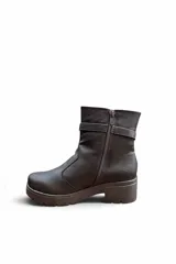 Bota corta de cuero color marrón con suela track y taco bloque. Incluye una tira decorativa en el tobillo con hebilla metálica dorada.