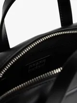 Cartera de mano tipo bowling color negro, confeccionada en poliuretano. Presenta doble asa superior, correa ajustable extraíble y el logo metálico de Tommy Jeans en la parte frontal.