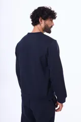 Buzo de felpa color negro, con cuello redondo, mangas largas y puños elásticos. Diseño básico y minimalista.