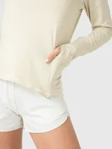 Polera de manga larga color marfil melange, con cuello alto y cierre frontal parcial. Presenta diseño deportivo con costuras visibles y puños con abertura para el pulgar.
