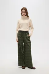 Pantalon de corte ancho y tiro alto, confeccionado en tela con estampado a cuadros en tonos verdes. Presenta cintura elástica con cordón de ajuste frontal.
