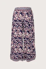 Pantalón de corte ancho y fluido con estampado geométrico en tonos azul marino, blanco y detalles en rojo. Presenta una cintura elástica con detalle de guarda decorativa y terminación similar en el ruedo.