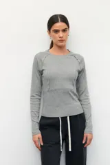 Remera de manga larga color blanco, confeccionada en algodón, con cuello redondo y diseño de costuras decorativas externas que realzan la silueta.