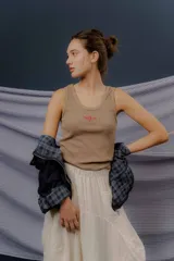 Musculosa básica de tejido acanalado color blanco, con escote redondo, calce al cuerpo y el logo NSLD bordado en el centro del frente.