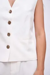 Chaleco blanco con cuello en V y cierre frontal con botones.