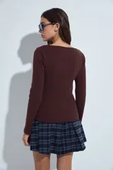 Remera de manga larga con escote cruzado en V, confeccionada en tejido elástico entallado al cuerpo.