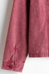 Campera de algodón color rosa con efecto acid wash, cierre frontal, cuello camisero, bolsillos delanteros ribeteados y puños con botón.
