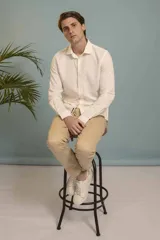 Camisa de manga larga en color salmón con estampado de pequeños motivos geométricos oscuros, cuello clásico y cierre frontal con botones.