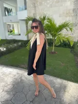 Vestido corto color beige, con escote en V con borde blanco, breteles anchos con lazos y corte holgado.