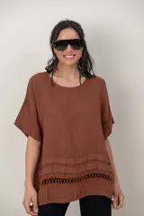 Blusa de lino color blanco, de corte amplio, con escote redondo, mangas cortas y detalle de guarda calada horizontal en la parte inferior.