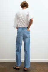 Jeans de tiro alto, pierna ancha y largo al tobillo, en denim celeste claro con efecto lavado. Presenta costura marcada en el centro de cada pierna y cierre frontal con cremallera y botón.