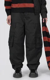 Pantalón cargo oversize de microfibra pesada en color negro, con silueta estructurada, bolsillos laterales de gran tamaño con solapa y broches snap, cintura elástica con cordón de ajuste y cierre frontal.