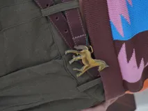 Cinturón de cuero marrón con hebilla metálica dorada en forma de caballo.