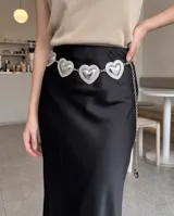 Cinto de metal plateado con diseño de dijes en forma de corazón repujado unidos por cadenas y tira colgante.